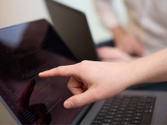 Two developers reading through Stockpilot API code on a laptop